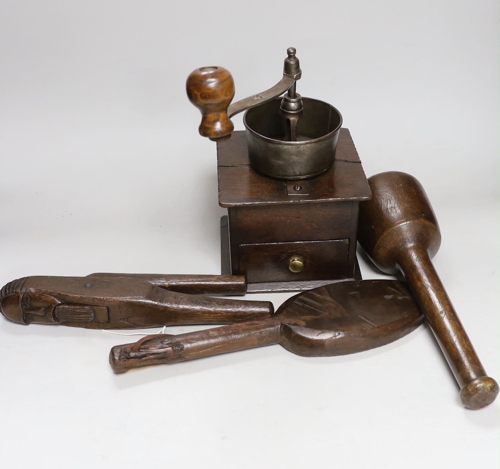Treen comprising, oak nutcracker, butter mould, pestle and coffee mill, the largest 31cm in length